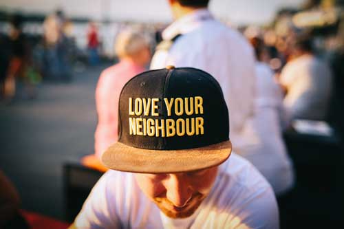 man wearing hat that reads Love Your Neighbor.