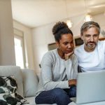 Couple looking at a laptop in their living room.