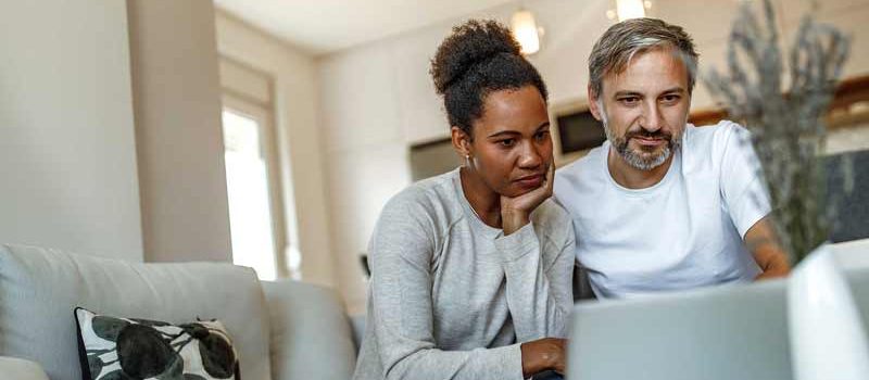 Couple looking at a laptop in their living room.