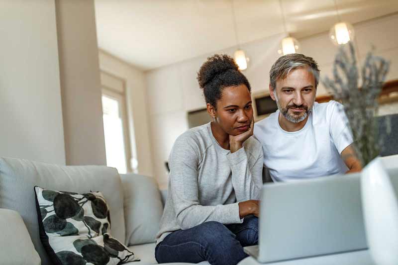 Couple looking at a laptop in their living room.