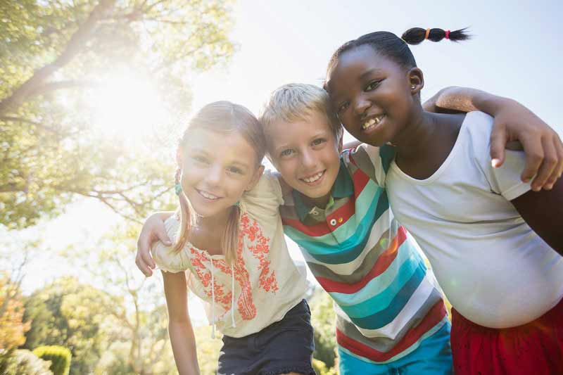 Group of children smiling outside.