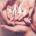 Hands holding a paper cut out of a family