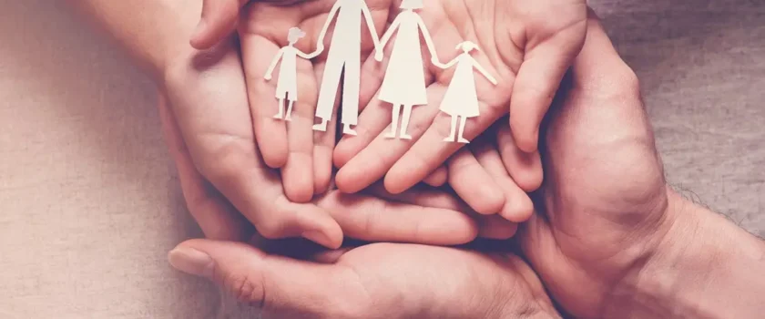Hands holding a paper cut out of a family