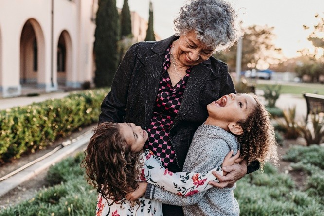 Grandmother embracing two children outside in a garden