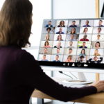Woman sitting at a desk with a virtual meeting on the desktop screen