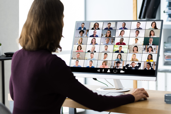 Woman sitting at a desk with a virtual meeting on the desktop screen
