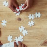 Hands assembling a puzzle made of blank pieces