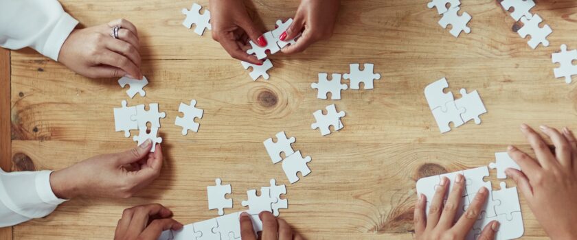 Hands assembling a puzzle made of blank pieces